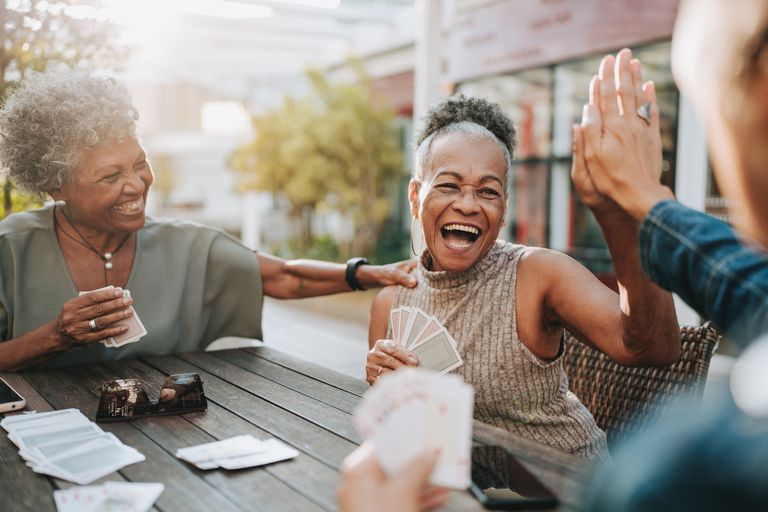 Senior female friends socializing playing cards outside