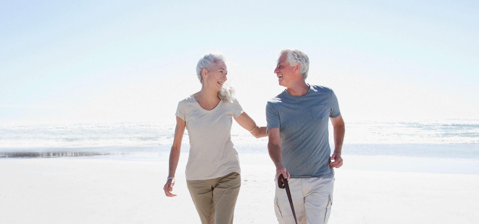 Couple walking on beach with their dog