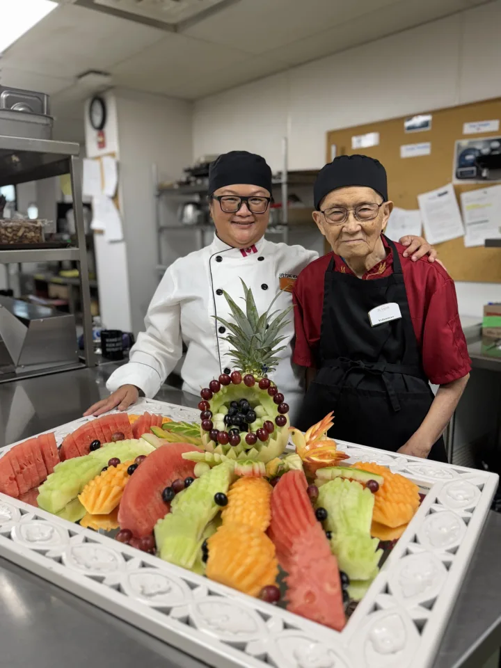 Sunrise team member and grandfather with fruit sculpture