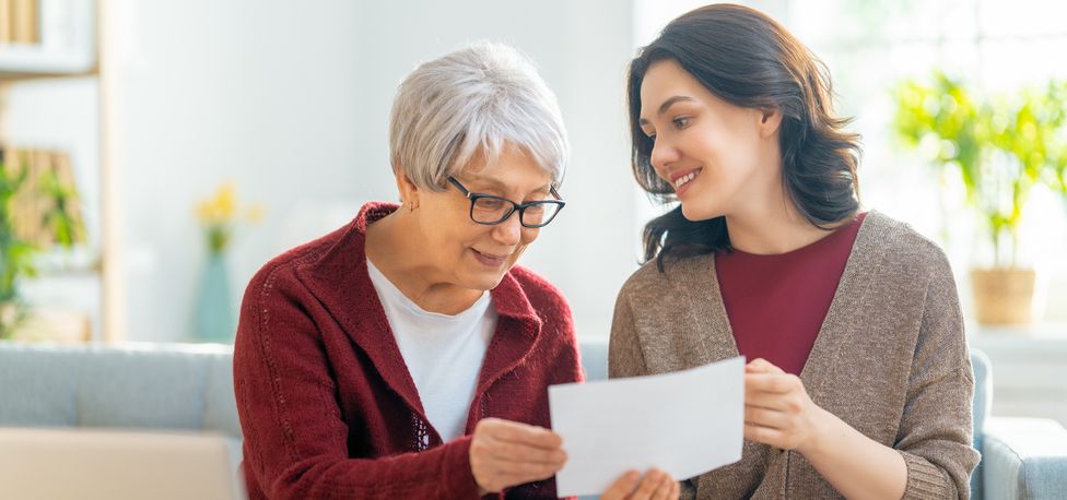 Senior woman and daughter looking at finances