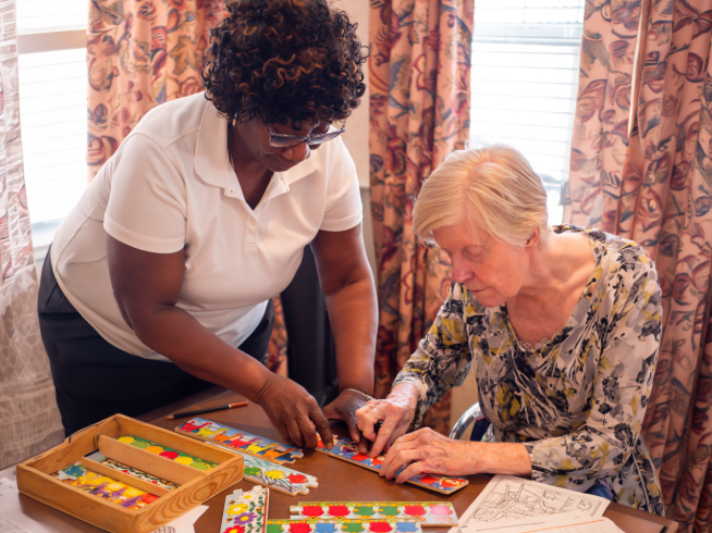 A nurse helping a memory care resident complete a puzzle at Sunrise of Paramus.