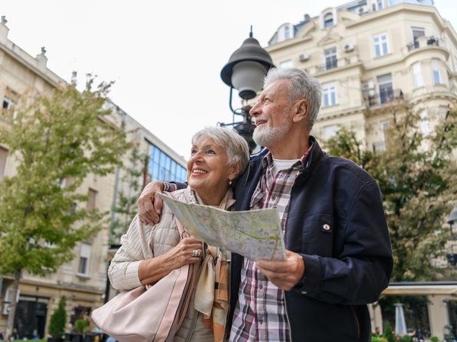 Senior couple walking around and sightseeing with a map.