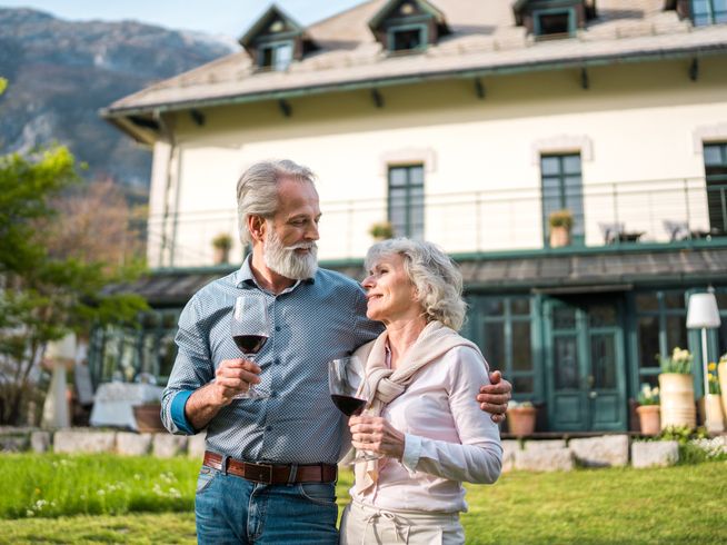 Senior couple enjoying wine outdoors in front of mountain views.