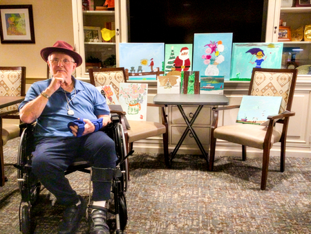 Senior living resident in front of his paintings