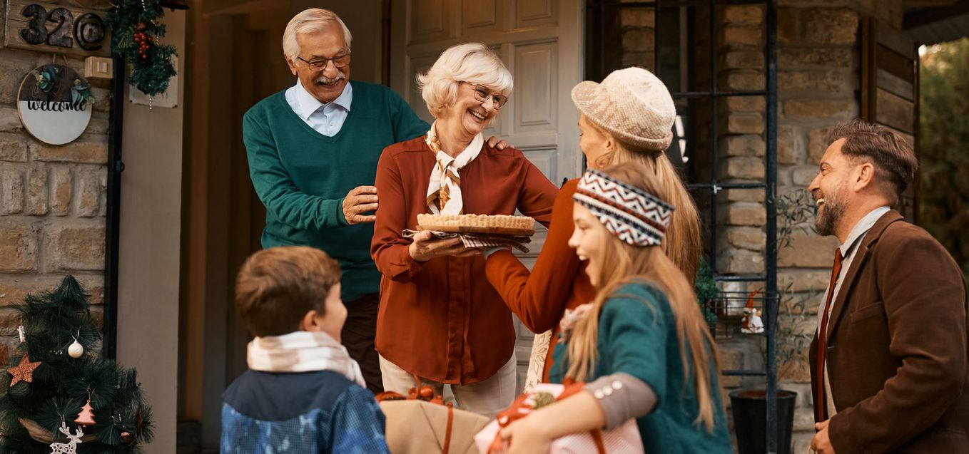 Senior couple welcoming family at the front door