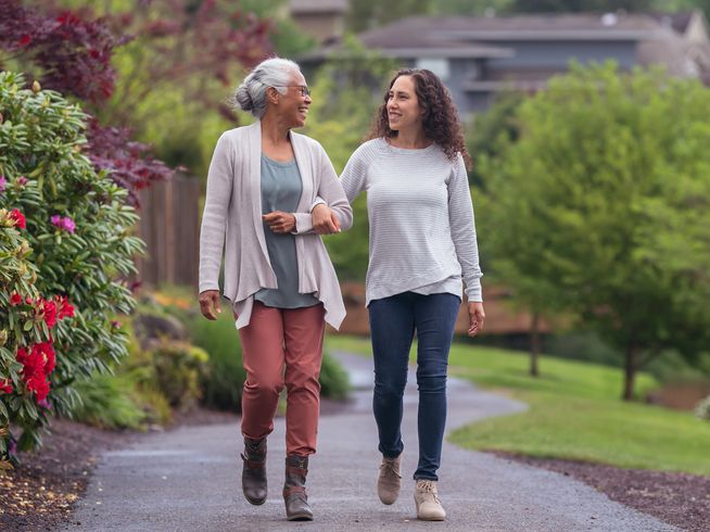 Senior living resident walking outside with daughter