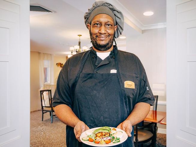 Senior living chef holding a plated meal