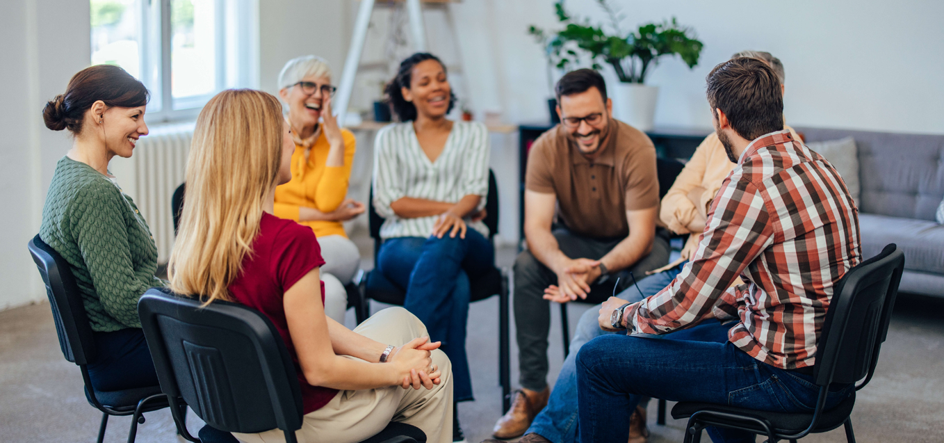 Group of people laugh together at a support group meeting