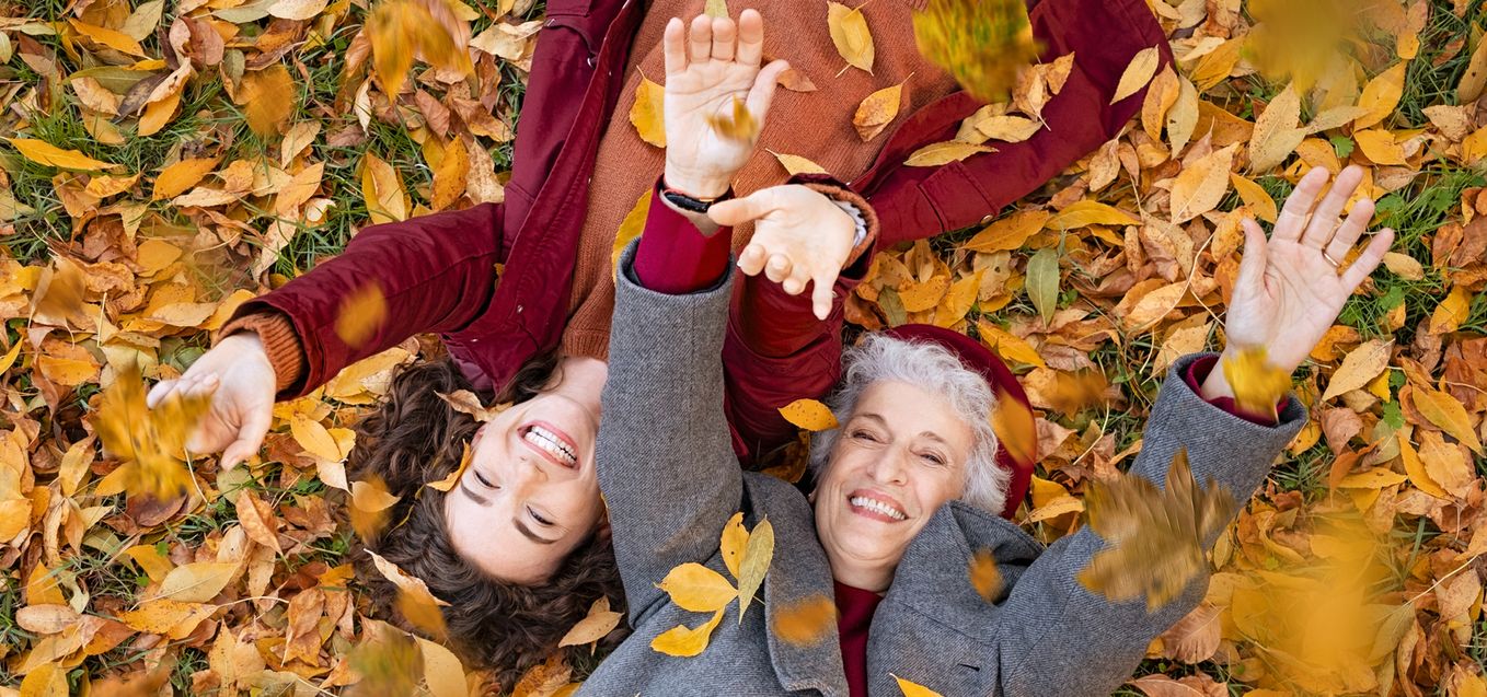 Senior and daughter laying in fall leaves