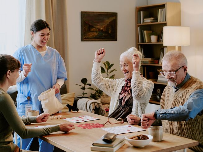 Seniors playing a game of bingo in a community with a nurse supervising and facilitating the game.