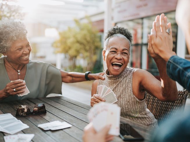 A group of seniors laughing and playing cards together.