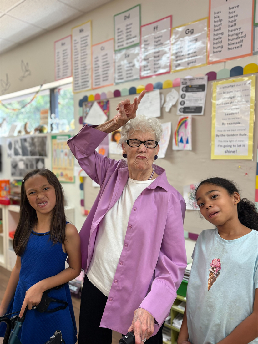 A Sunrise Senior Living resident visiting an elementary school classroom and making silly faces with students.